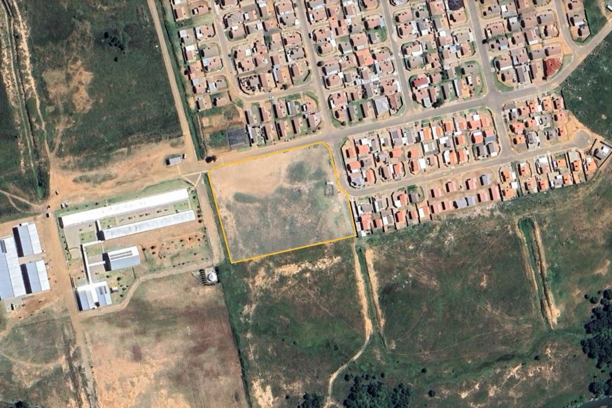 An aerial view of a vacant residential land plot highlighted in yellow, situated within an established suburban neighborhood.