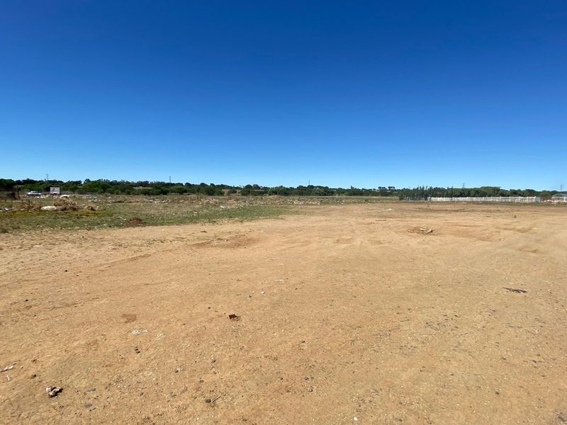 A wide-angle view of a vacant residential plot of land with natural ground cover and clear horizon.