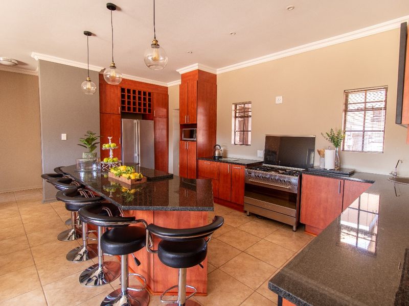 Spacious kitchen featuring cherry wood cabinetry, granite countertops, a central island with breakfast bar seating, and a stainless steel gas stove.