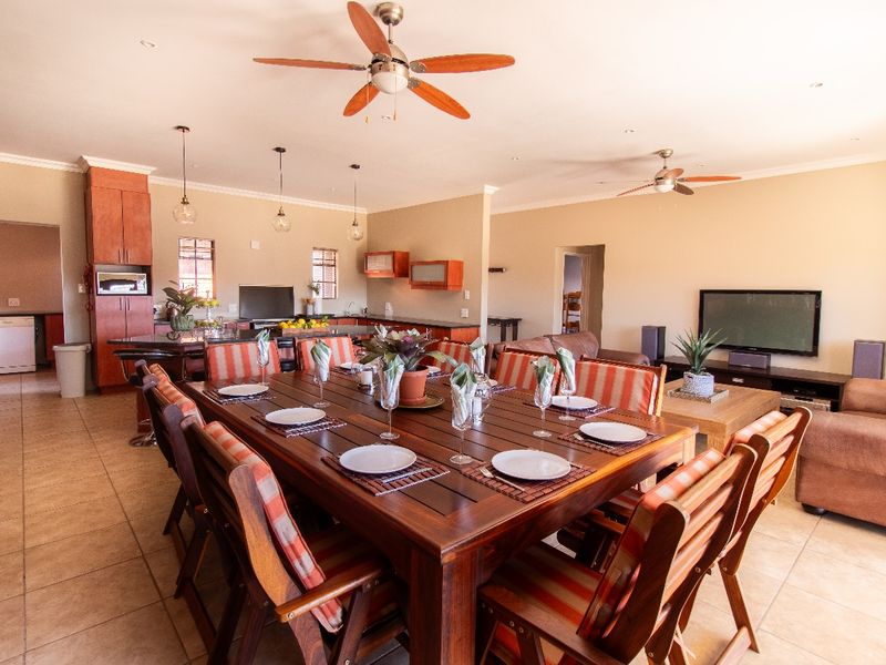 Spacious open-plan living and dining area featuring tiled floors, ceiling fans, and a functional kitchen with built-in cabinetry and appliances.
