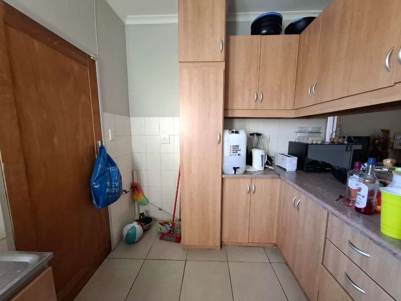A functional kitchen featuring laminate cabinetry, tiled backsplash, and tiled flooring, offering a practical layout with ample storage space.