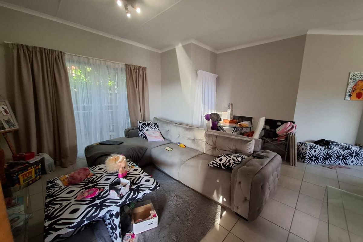 A living room featuring tiled flooring, coved ceilings, and a sliding glass door providing access to the exterior.
