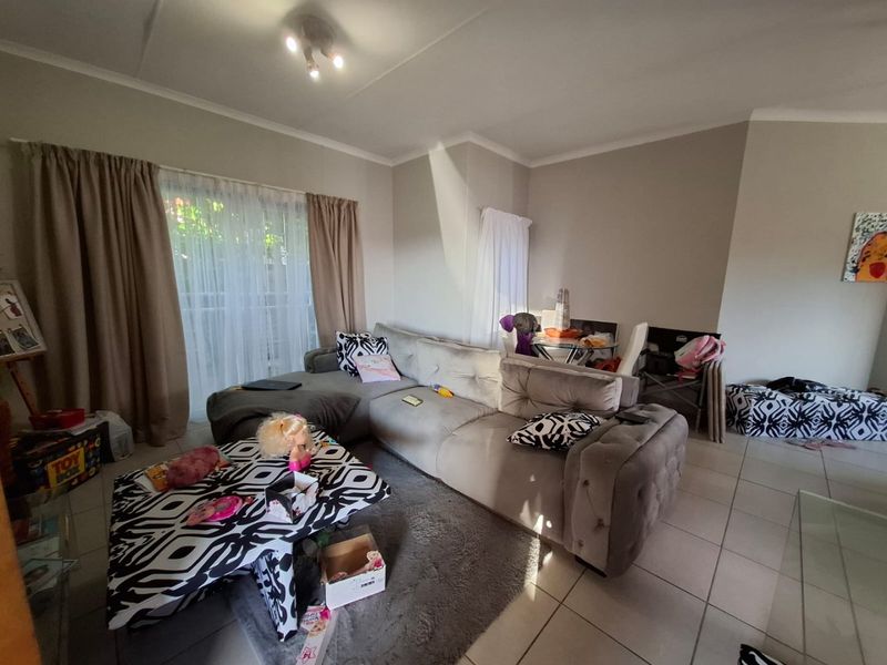 A living room featuring tiled flooring, coved ceilings, and a sliding glass door providing access to the exterior.