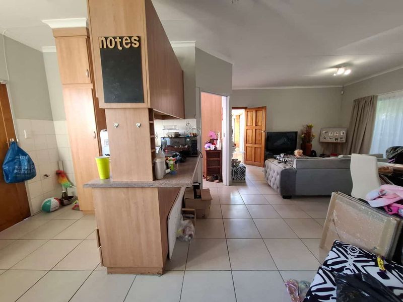Open plan living area featuring tiled flooring and a kitchen with laminate cabinetry, connecting to the main living space.