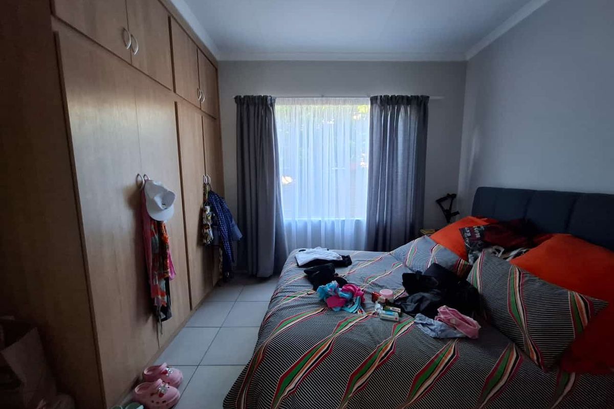 A functional bedroom featuring built-in wooden cupboards and tiled flooring, providing ample storage space and a neutral foundation for interior design.