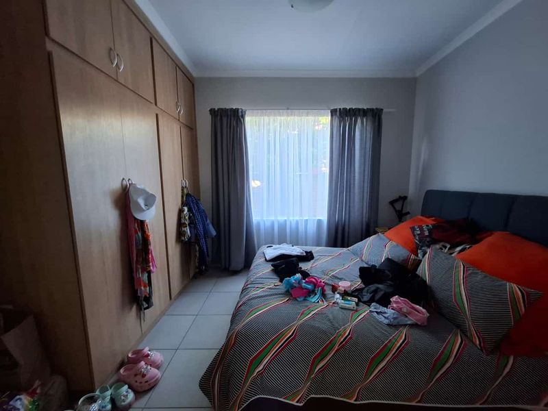 A functional bedroom featuring built-in wooden cupboards and tiled flooring, providing ample storage space and a neutral foundation for interior design.