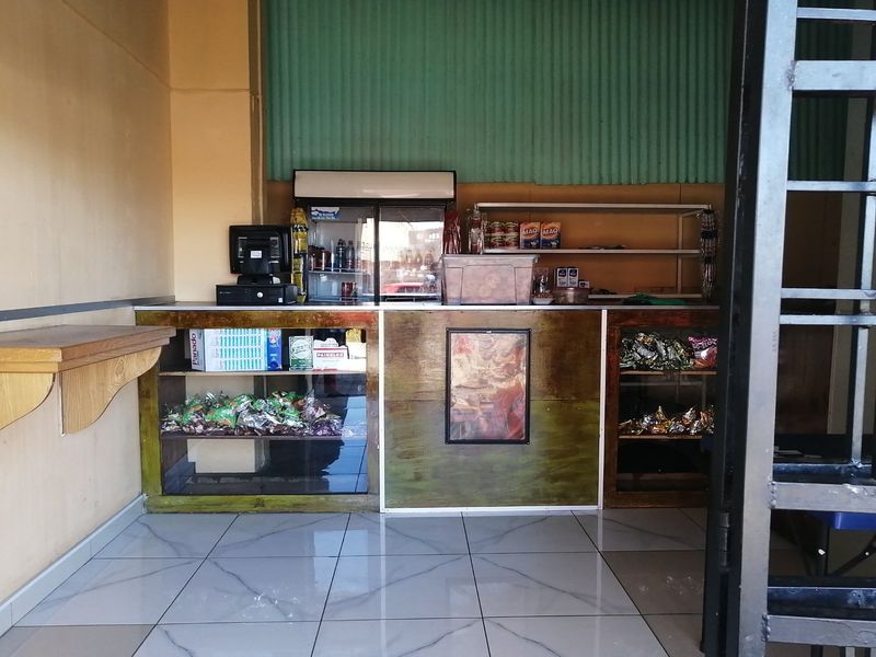 A commercial service counter area featuring tiled flooring, built-in shelving, and corrugated metal wall accents, suitable for retail or service operations.