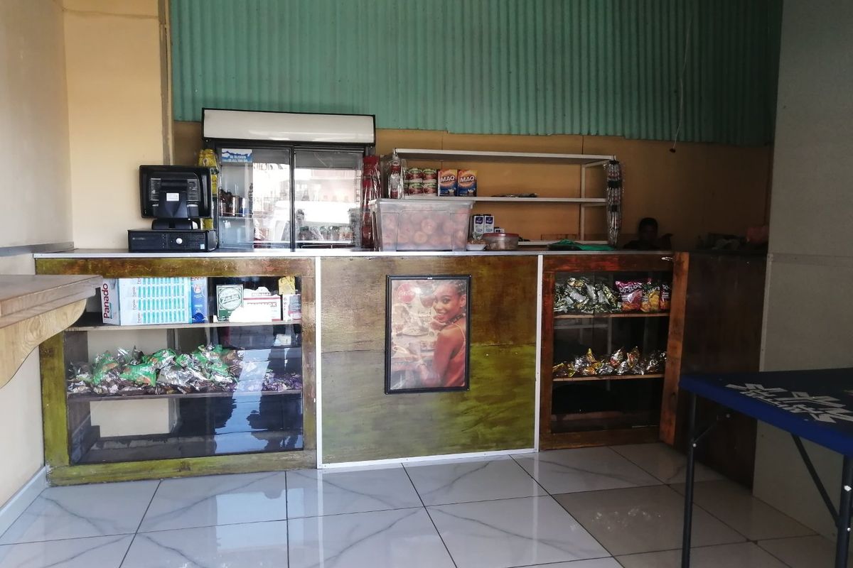 A commercial service counter area featuring tiled flooring, built-in shelving, and corrugated metal wall cladding, suitable for retail or service operations.