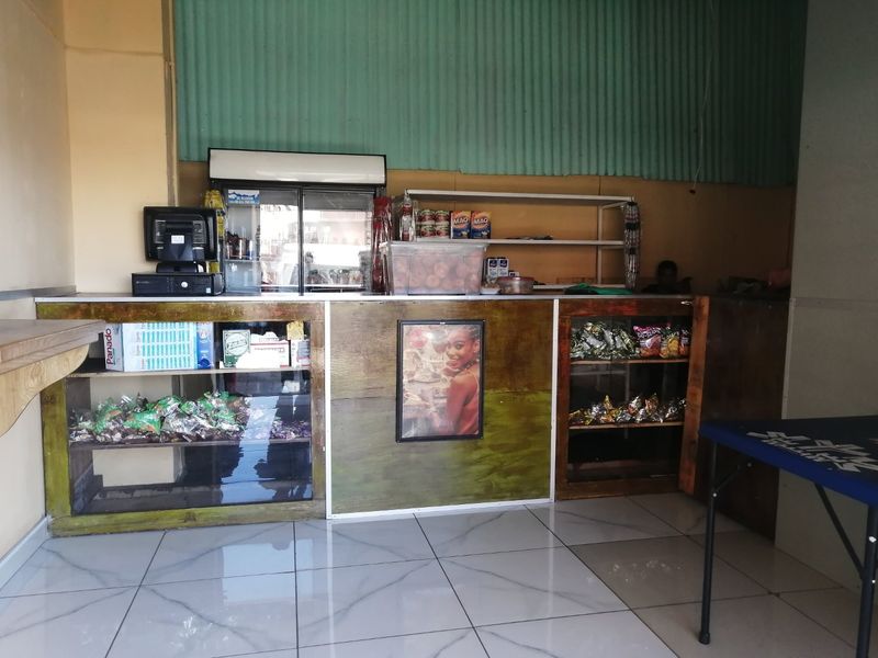 A commercial service counter area featuring tiled flooring, built-in shelving, and corrugated metal wall cladding, suitable for retail or service operations.