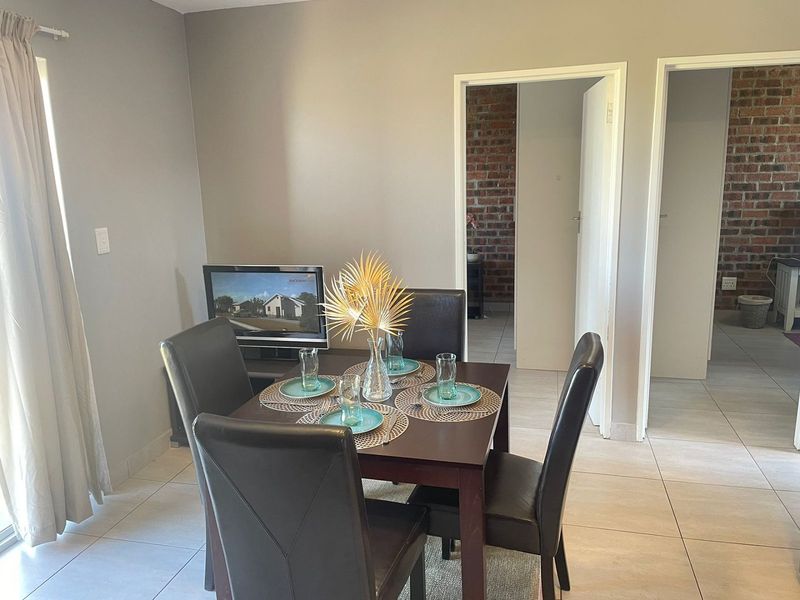 A dining area featuring tiled flooring and an exposed brick wall, providing a neutral backdrop for meals.