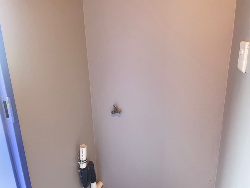 A dedicated laundry utility space featuring a wall-mounted water tap and exposed plumbing connections, ready for appliance installation.