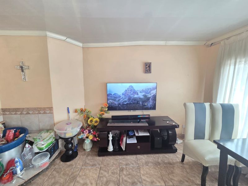 A living room area featuring tiled flooring and coved ceiling details, currently showing signs of wear and maintenance requirements.