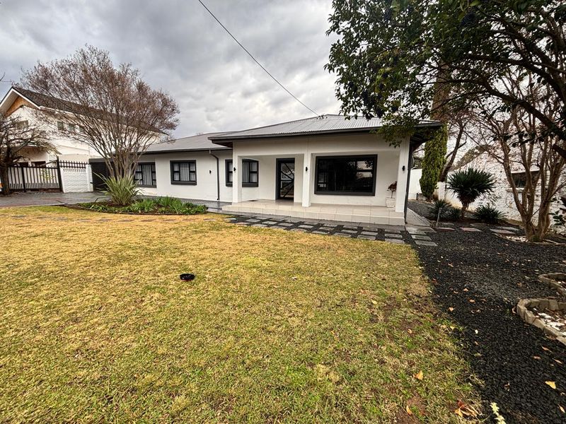 A well-maintained single-story home featuring a covered front porch, modern dark-framed windows, and a neatly landscaped front garden with paved pathways.
