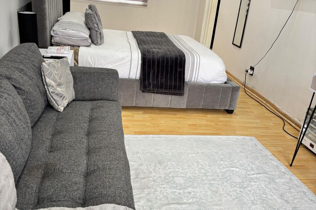 A well-maintained bedroom featuring light-toned laminate flooring and modern roller blinds, offering a clean and functional living space.