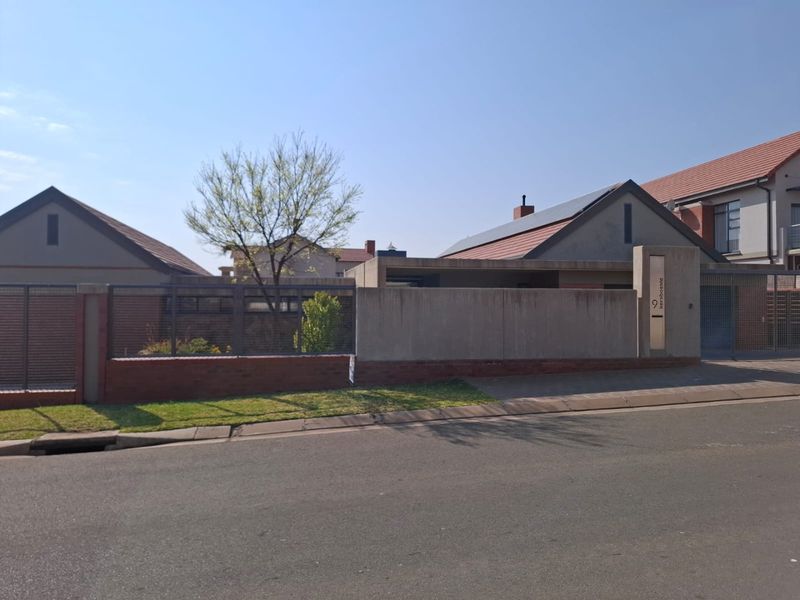 Front exterior view of a residential property featuring a concrete and brick boundary wall, tiled roof, and solar panels.