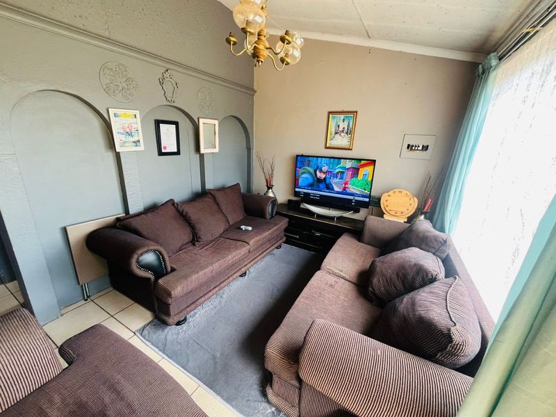 A living room featuring decorative wall arches, tiled flooring, and a central chandelier, offering a dated aesthetic ready for modernization.