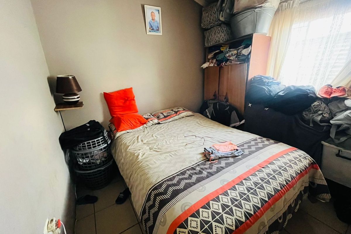 A compact bedroom featuring tiled flooring and a built-in cupboard, offering a functional space for rest.