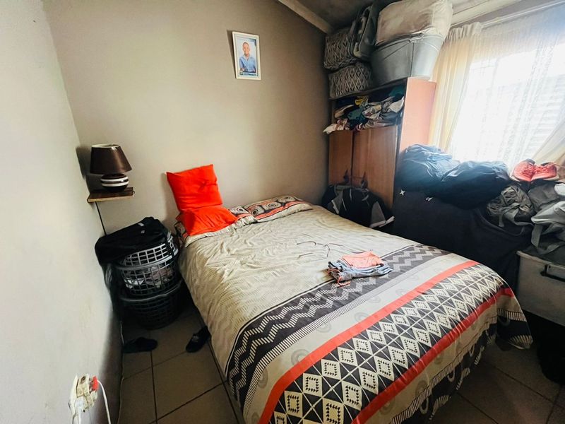 A compact bedroom featuring tiled flooring and a built-in cupboard, offering a functional space for rest.