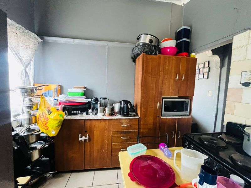 A compact kitchen featuring wooden cabinetry, built-in microwave, and electric stove, requiring cosmetic updates to improve the overall aesthetic and functionality.