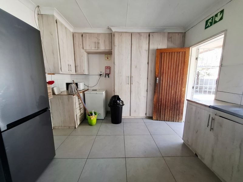A functional kitchen featuring light-toned built-in cabinetry, tiled flooring, and direct access to an outdoor area.