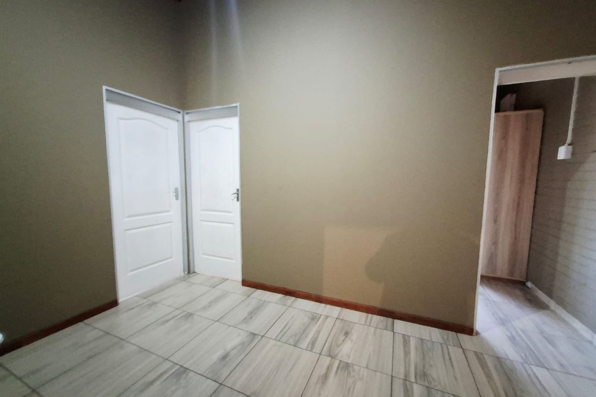 An empty bedroom featuring neutral wall paint, tiled flooring, and two internal doors leading to adjacent spaces.