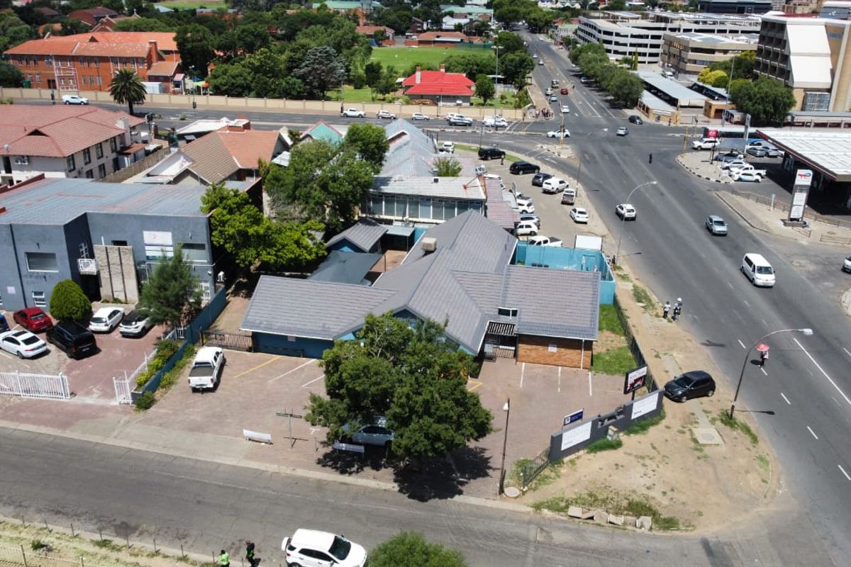 Aerial view of a commercial property featuring a tiled roof building, paved parking area, and direct access to a main road intersection.