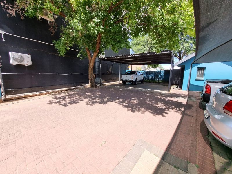 Commercial property exterior featuring a paved driveway and a covered carport area with adjacent building wall and external air conditioning unit.