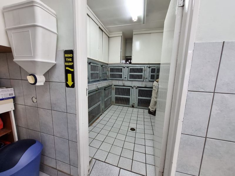 A functional utility space featuring tiled surfaces, built-in cabinetry, and integrated metal enclosures, suitable for commercial animal care or specialized storage purposes.