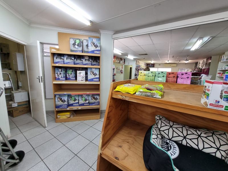 Commercial retail space featuring tiled flooring, suspended ceiling, and built-in wooden shelving units for product display.