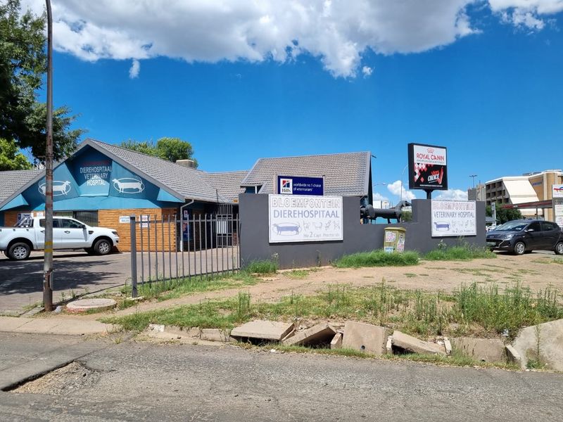 Front exterior view of the Bloemfontein Veterinary Hospital featuring a tiled roof, brick facade, and prominent commercial signage with paved parking area.