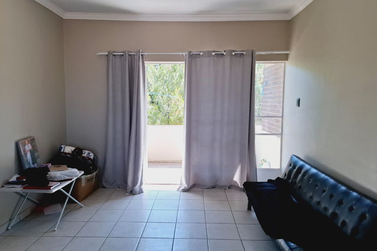 A living room featuring neutral tiled flooring and a sliding glass door providing access to an outdoor balcony area.