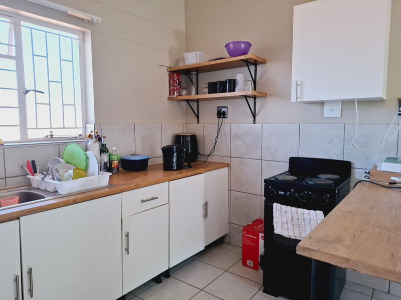 A functional kitchen featuring built-in cabinetry, wooden countertops, a tiled backsplash, and a freestanding stove, offering a practical layout for daily meal preparation.
