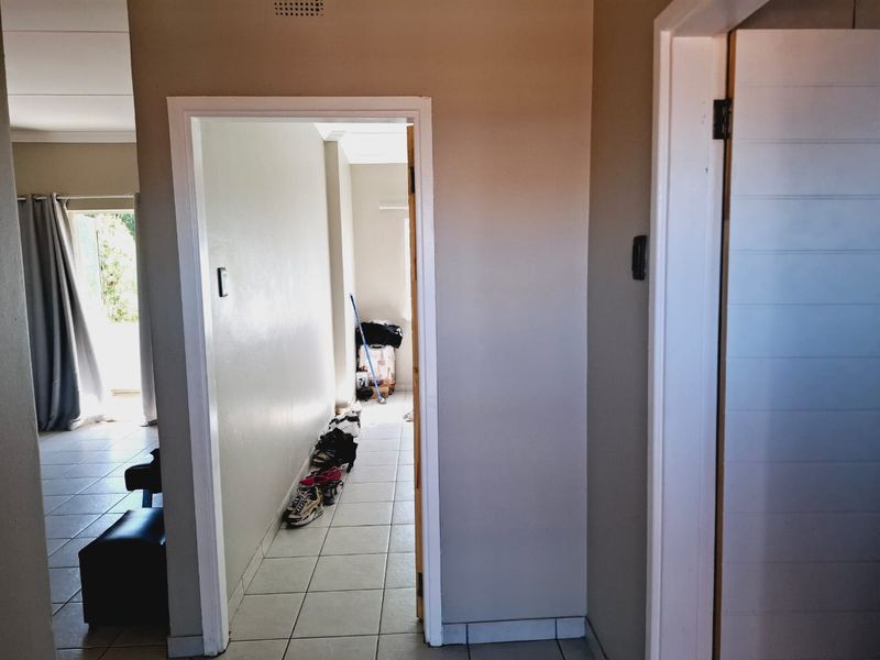 A functional hallway connecting living areas, featuring neutral wall tones and tiled flooring throughout.