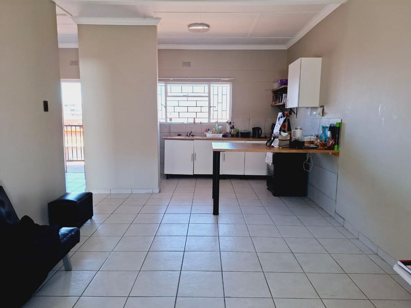 Open plan living and kitchen area featuring tiled flooring, functional cabinetry, and direct access to a balcony.