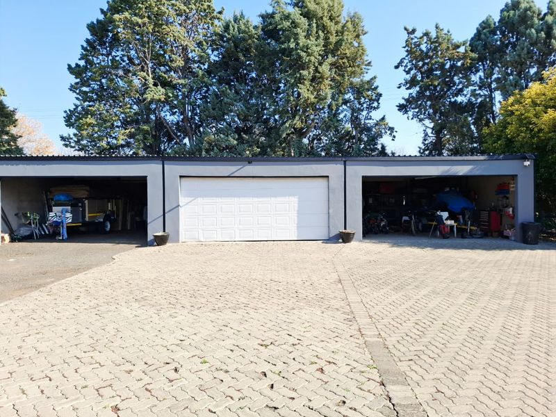 A triple garage featuring a paved driveway and a central sectional garage door, providing ample parking and storage space.