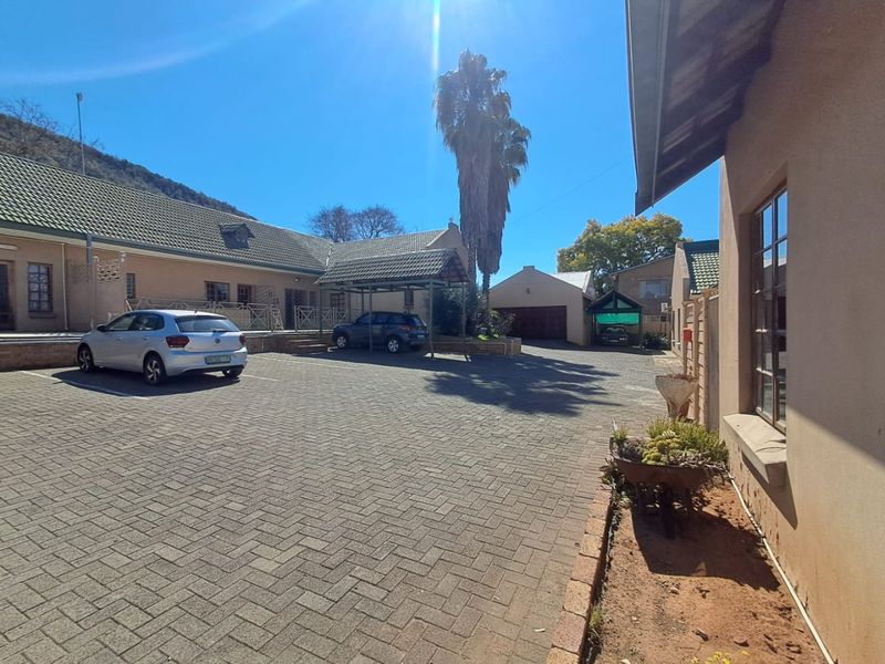 Spacious paved driveway and courtyard area featuring a carport, garage, and access to the main townhouse building.