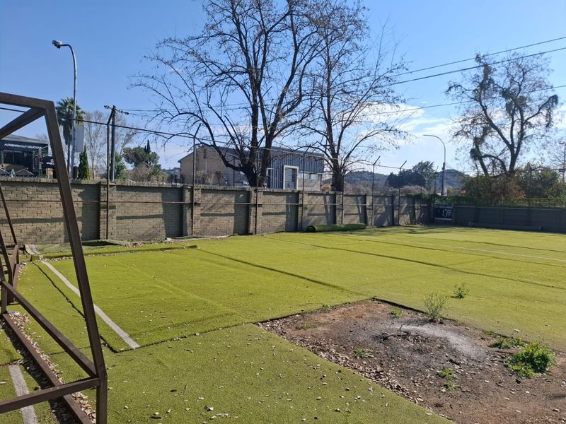 Outdoor sports facility featuring an artificial turf surface enclosed by a perimeter brick wall and security fencing.