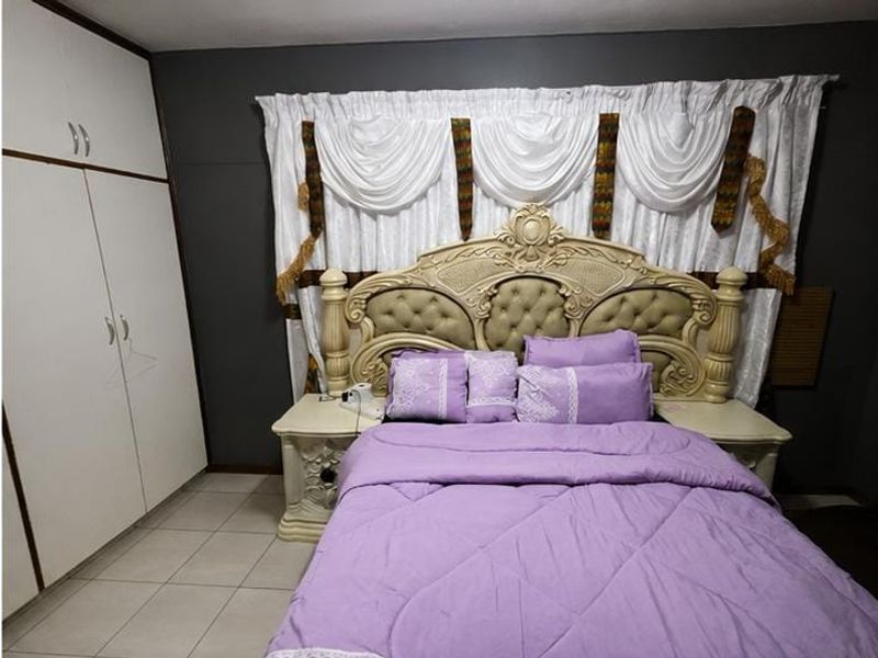 A bedroom featuring built-in cupboards and tiled flooring, providing a functional space with neutral wall tones.