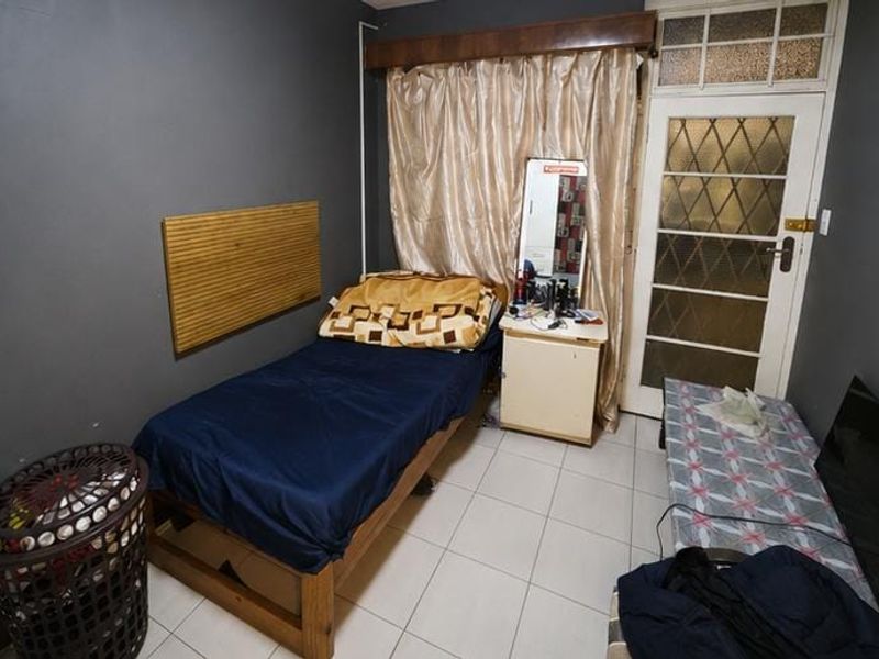 A compact bedroom featuring tiled flooring and a classic leaded glass door leading to an exterior space.