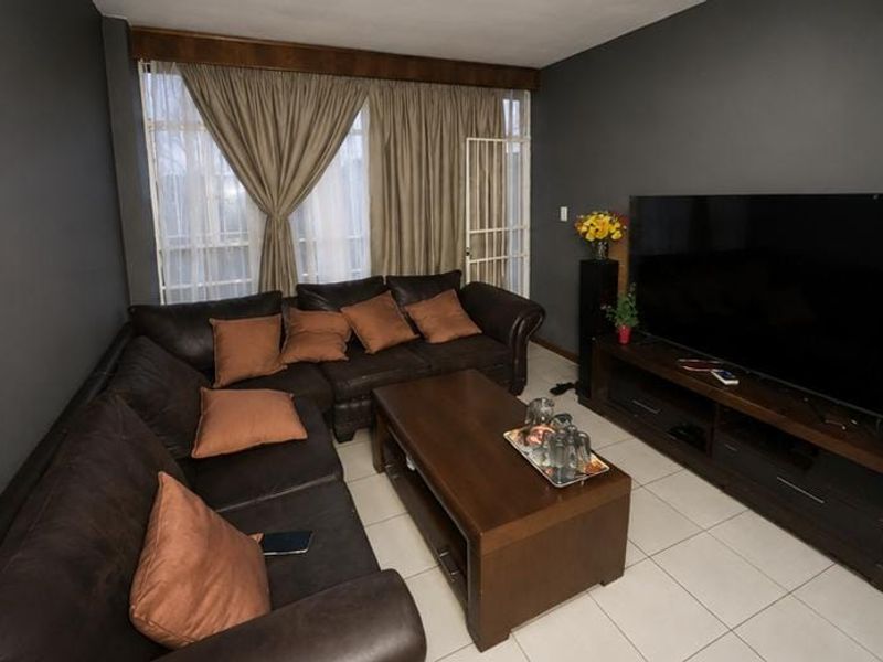 A living room featuring tiled flooring and a sliding door with an integrated security gate, providing access to the exterior.