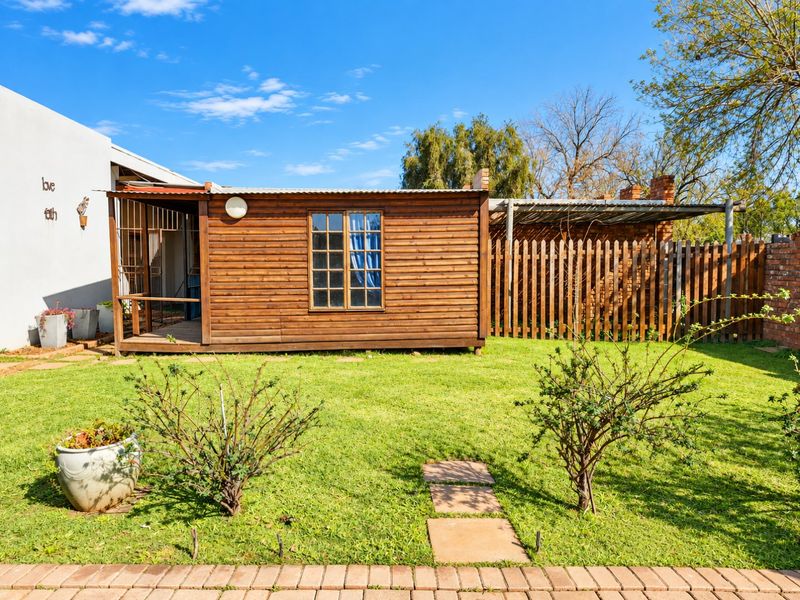 A well-maintained rear garden featuring a timber cabin, lawn area, and a wooden picket fence, providing a private outdoor space.