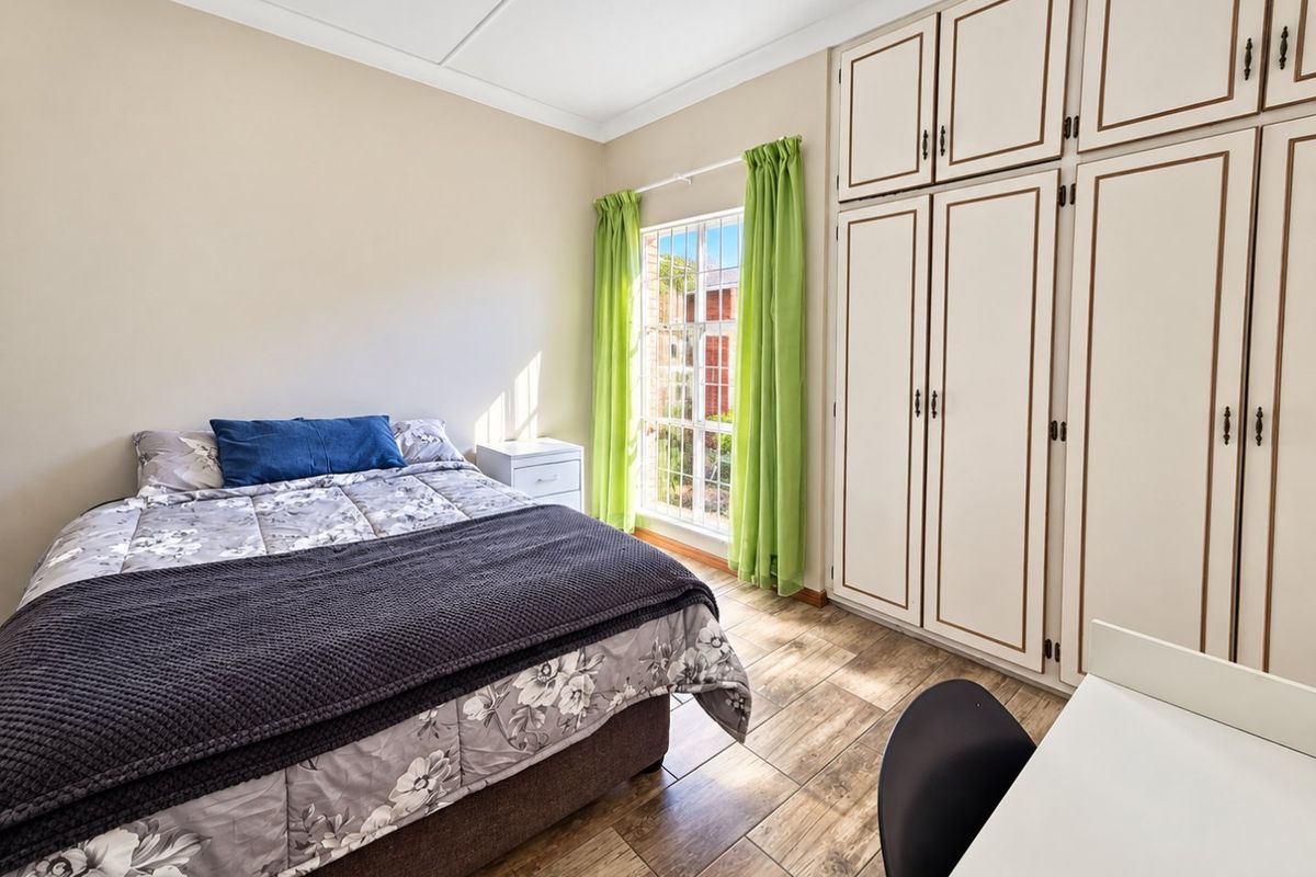A well-lit bedroom featuring wood-look tiled flooring and extensive floor-to-ceiling built-in cabinetry providing ample storage space.