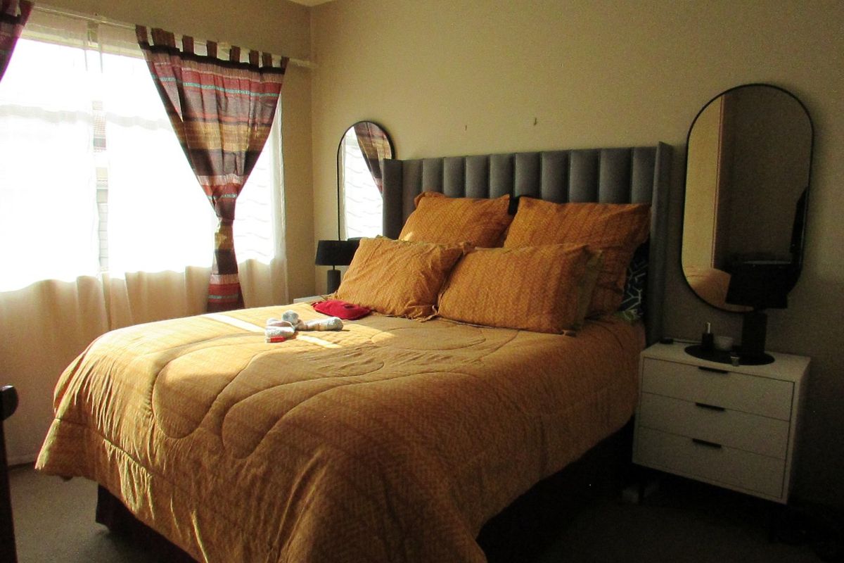 A standard bedroom featuring carpeted flooring and a window, providing a functional space for rest.