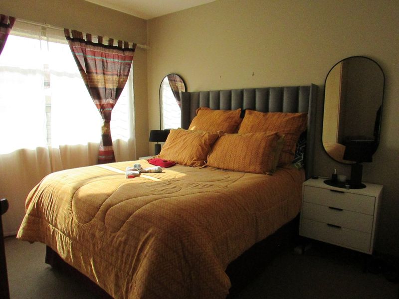 A standard bedroom featuring carpeted flooring and a window, providing a functional space for rest.