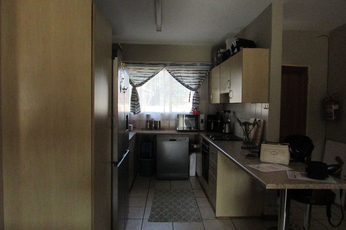 A functional kitchen featuring built-in cabinetry, laminate countertops, tiled flooring, and a breakfast bar, offering a practical layout for daily meal preparation.