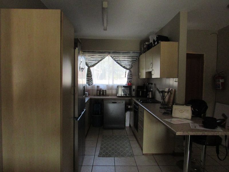 A functional kitchen featuring built-in cabinetry, laminate countertops, tiled flooring, and a breakfast bar, offering a practical layout for daily meal preparation.
