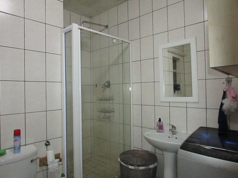 A functional bathroom featuring a shower enclosure, pedestal basin, and toilet, finished with full-height wall tiling.