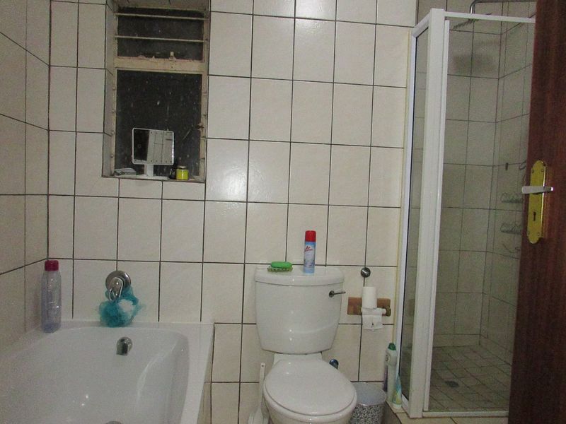 A functional bathroom featuring a bathtub, separate shower enclosure, and toilet, finished with full-height wall tiling.