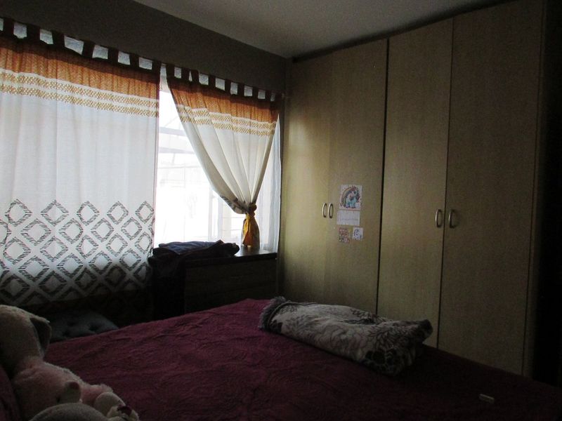 A bedroom featuring built-in cupboards and natural light from a window.