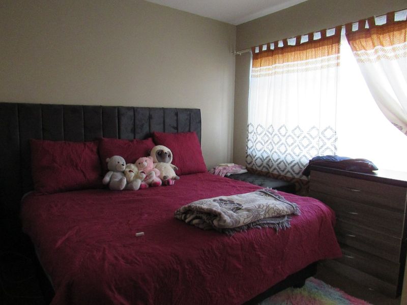 A bedroom featuring neutral wall tones and a window with installed curtain rods, providing a functional space for rest.